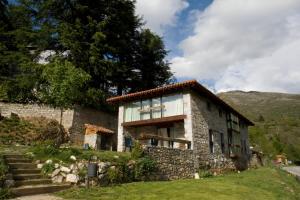 une maison en pierre sur une colline avec des montagnes en arrière-plan dans l'établissement Apartamentos Rurales El Lleron, à Caso