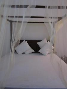 łóżko z białymi poduszkami i baldachimem w obiekcie Sanderling Silent Beach Cabanas w Tangalli
