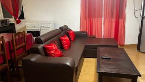 a living room with a leather couch and red pillows at Villa Cali SONOMA in Sambava