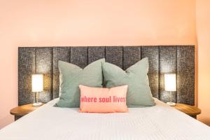 Bett mit einem großen Kopfteil mit einem rosa Kissen in der Unterkunft Bold & Floral Little Richard Getaway in Macon