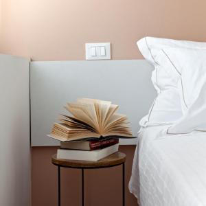 a stack of books on a table next to a bed at Al Ponticello in Castelfranco Veneto