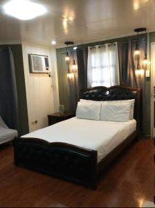 a bedroom with a large bed with white sheets at Mabale’s Homestead in Cagayan de Oro
