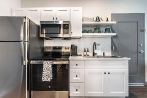 a kitchen with white cabinets and a stainless steel refrigerator at Chill Like Gregg Sunlit Southern Vibe in Macon