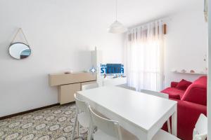 salon z białym stołem i czerwoną kanapą w obiekcie Condominio International w mieście Lido di Jesolo