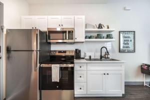 Una cocina con gabinetes blancos y un refrigerador de acero inoxidable. en Turn Back Time Cher-Inspired Escape, en Macon