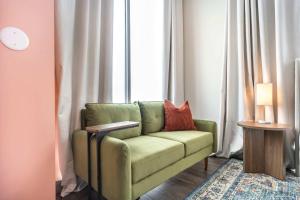 un sofá verde en una habitación con ventana en Turn Back Time Cher-Inspired Escape, en Macon