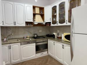 a kitchen with white cabinets and a refrigerator at LuxurySeaview Apartment in Durrës