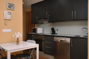 a kitchen with black cabinets and a white table at Cómodo luminoso y céntrico by CABANA Rentals in Vigo +18 photos