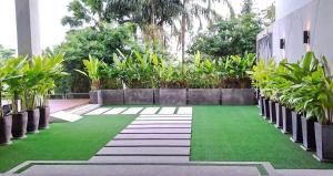 un giardino con erba verde e piante in un edificio di At the tree by fatimah R315 a Rawai Beach