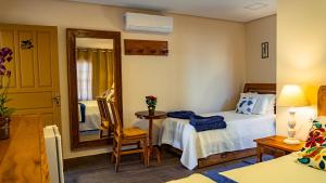 a bedroom with a bed and a table and a mirror at Pousada Charme Tiradentes in Tiradentes