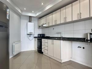 a kitchen with white cabinets and a sink and a stove at Gray Fox Apartments - Antártida in Ushuaia +37 photos