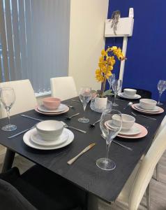 a table with plates and wine glasses on it at Betty's Apartment- Metres From Train Station in Harrogate +12 photos