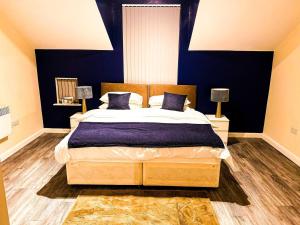 a bedroom with a large bed with blue walls at Betty's Apartment- Metres From Train Station in Harrogate