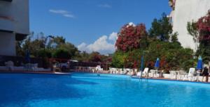 a large swimming pool with white chairs and tables at Chira House in Santa Marinella