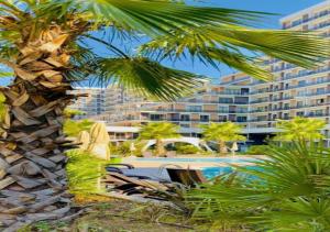 Un hombre de pie junto a una palmera al lado de un edificio. en Dimer country, en Beylikduzu