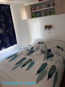 Una cama con un edredón con hojas. en Mobil-home, en Saint-Pair-sur-Mer