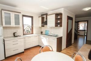 una cucina con mobili bianchi, tavolo e sedie di Wielorybek Junior a Kąty Rybackie