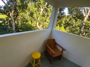 una sedia in legno seduta in una stanza con due finestre di Villa Silva&Braga POUSADA arraial d'ajuda Bahia-VERDE a Arraial d'Ajuda