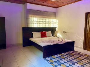 Un dormitorio con una cama con una almohada roja encima. en Lavimac Royal Hotel, en Kumasi