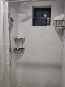 ein Bad mit einer Dusche und weißen Fliesen in der Unterkunft GRE homes Studio apartment in Ruaka