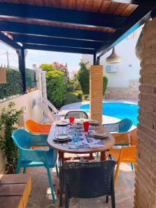 a patio with a table and chairs and a pool at Blue Paradise Seaview villa with private pool in Sounio
