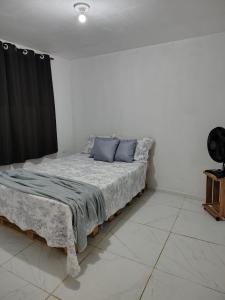 a bed with blue pillows in a white room at Vila Negreiros Serra Negra Casa 3 in Bezerros
