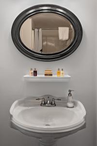 a bathroom sink with a round mirror above it at The Waterford Inn in Provincetown