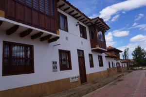 een wit gebouw met houten ramen aan een straat bij Hermoso Apartamento Faros de la Villa a 4 calles de la Plaza in Villa de Leyva