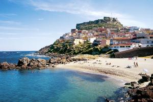 a beach with a group of people on the beach at Brezza Marina & L'oasi Blu in Castelsardo