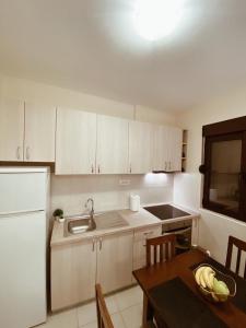 a kitchen with white cabinets and a table and a sink at Apartmani Vucetic MM in Igalo