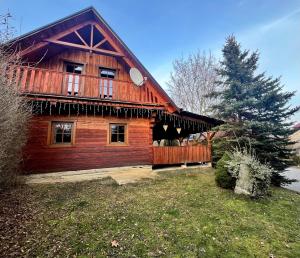 a log cabin with a porch and a tree at Drevenica Tatry No 1 in Liptovský Mikuláš
