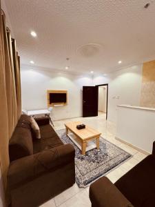 Una sala de estar con un sofá y una mesa de café. en عروس الشاطئ للشقق المخدومة, en Umm Lajj