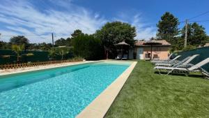 a swimming pool with chairs and a house at Gites les Bleuets in Salavas