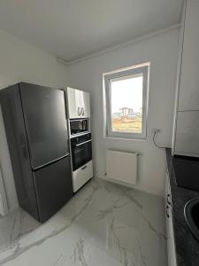 Il comprend une cuisine équipée d'un réfrigérateur en acier inoxydable et une fenêtre. dans l'établissement Affordable Cute & Comfy Flat, à Dobroeşti