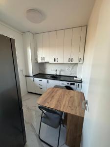 une cuisine avec une table en bois et des armoires blanches dans l'établissement Affordable Cute & Comfy Flat, à Dobroeşti 3 autres photos