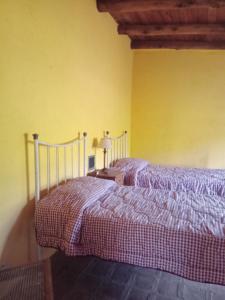 two beds in a bedroom with yellow walls at Casa Chakana in La Cumbre