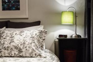 a bedroom with a bed and a lamp on a night stand at L'Adresse Botanique - Studio in Montréal