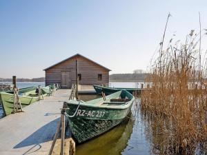 a green boat is docked at a dock at Ferienwohnung auf dem Fischerhof, Vipperow in Vipperow