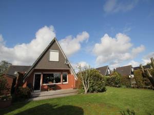a home with a pitched roof and a lawn at Ferienhaus Seeschwalbe in Dornumersiel in Dornumersiel
