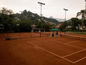 un campo da tennis con una persona in piedi sotto un ombrellone verde di resort comfort ad Araras Petropolis