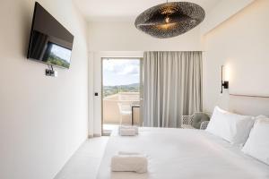 a white bedroom with a large bed and a tv at Levanda apart in Dassia