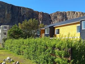 a yellow house with a mountain in the background at Kau Si Aike in El Chalten