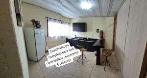 a kitchen with a refrigerator and a table and chairs at Flat na área central de Valadares Com AR garagem wifi cozinha completa para grupos ou casais in Governador Valadares
