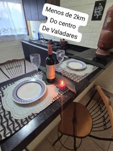 a table with two plates and a bottle of wine at Flat na área central de Valadares Com AR garagem wifi cozinha completa para grupos ou casais in Governador Valadares