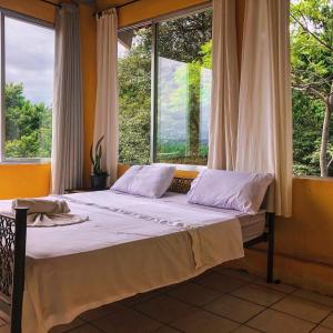 a bed in a room with a large window at Banana Leaf Eco Hostel in Barra de Guaratiba