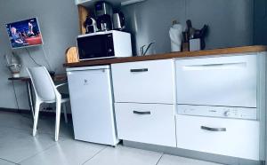 a kitchen with white cabinets and a microwave at Savane 82 - Vue mer - Accès plage in Le Gosier