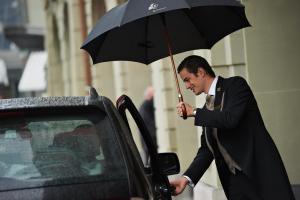 ベルンにあるHotel Schweizerhof Bern & Spaの車の横に傘を持つ男