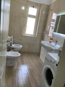 une salle de bain avec deux toilettes et un lavabo et une machine à laver dans l'établissement Double room with shared bathroom, à Tirana