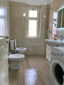 une salle de bain avec toilettes et lavabo et une machine à laver dans l'établissement Double room with shared bathroom, à Tirana