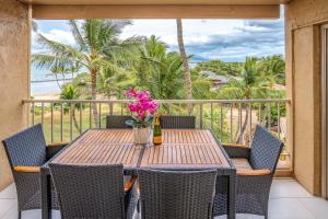 a wooden table with chairs and flowers on a balcony at Oceanfront Modern & Elegant Vistas in Kihei